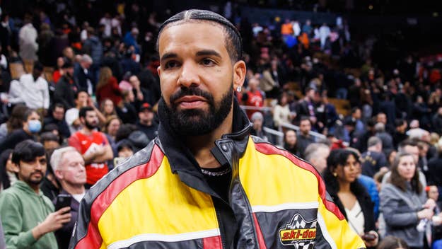 Drake in a racing jacket with a crowd in the background at an event