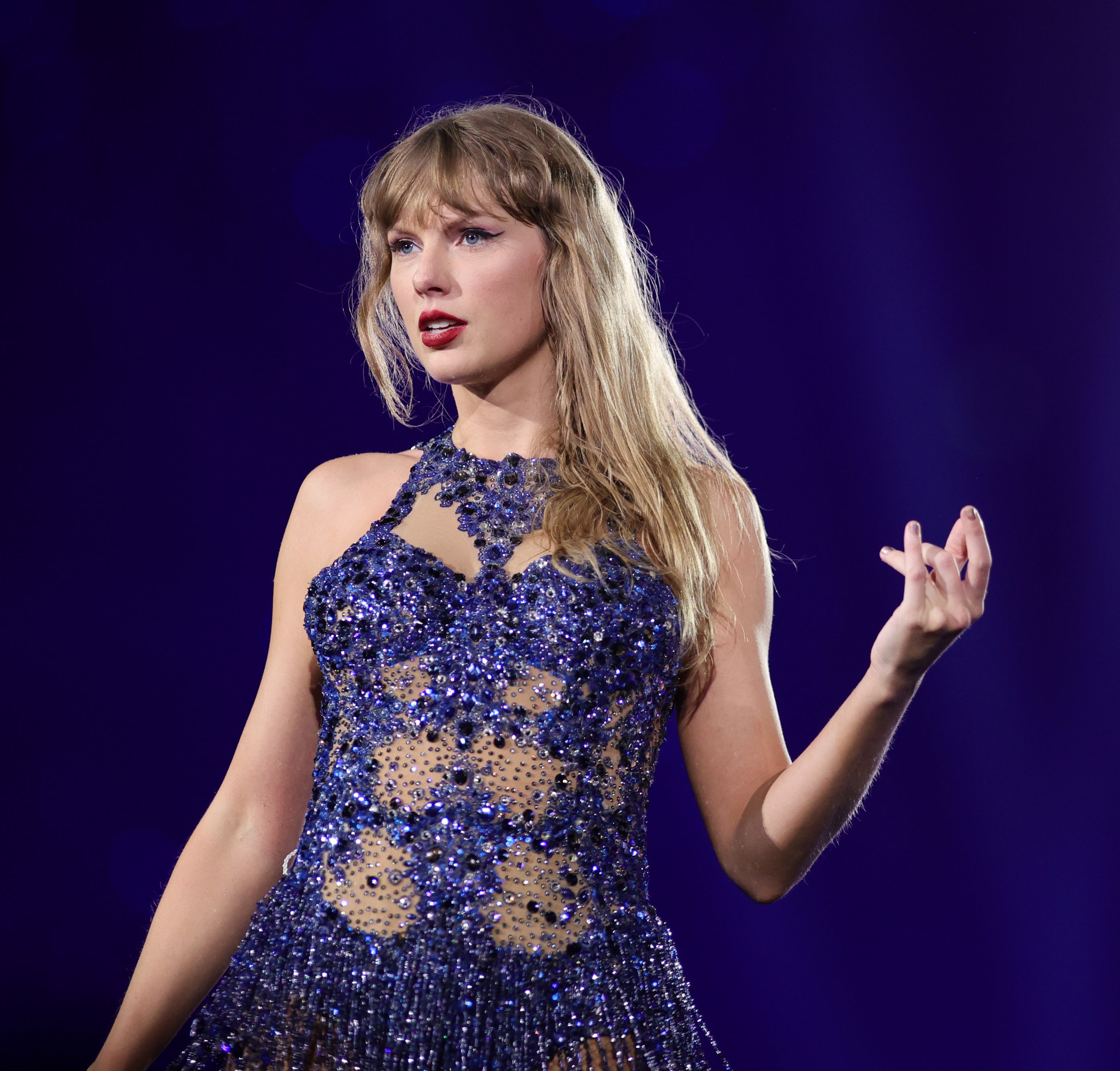 Taylor Swift performs on stage in a sparkling, intricately designed dress