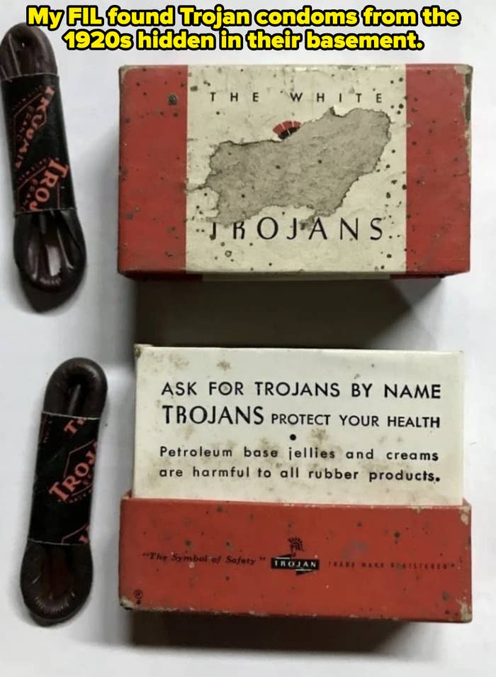 Three vintage Trojan condom packages, two opened to show advertising text about health benefits, and two unwrapped condoms next to the boxes