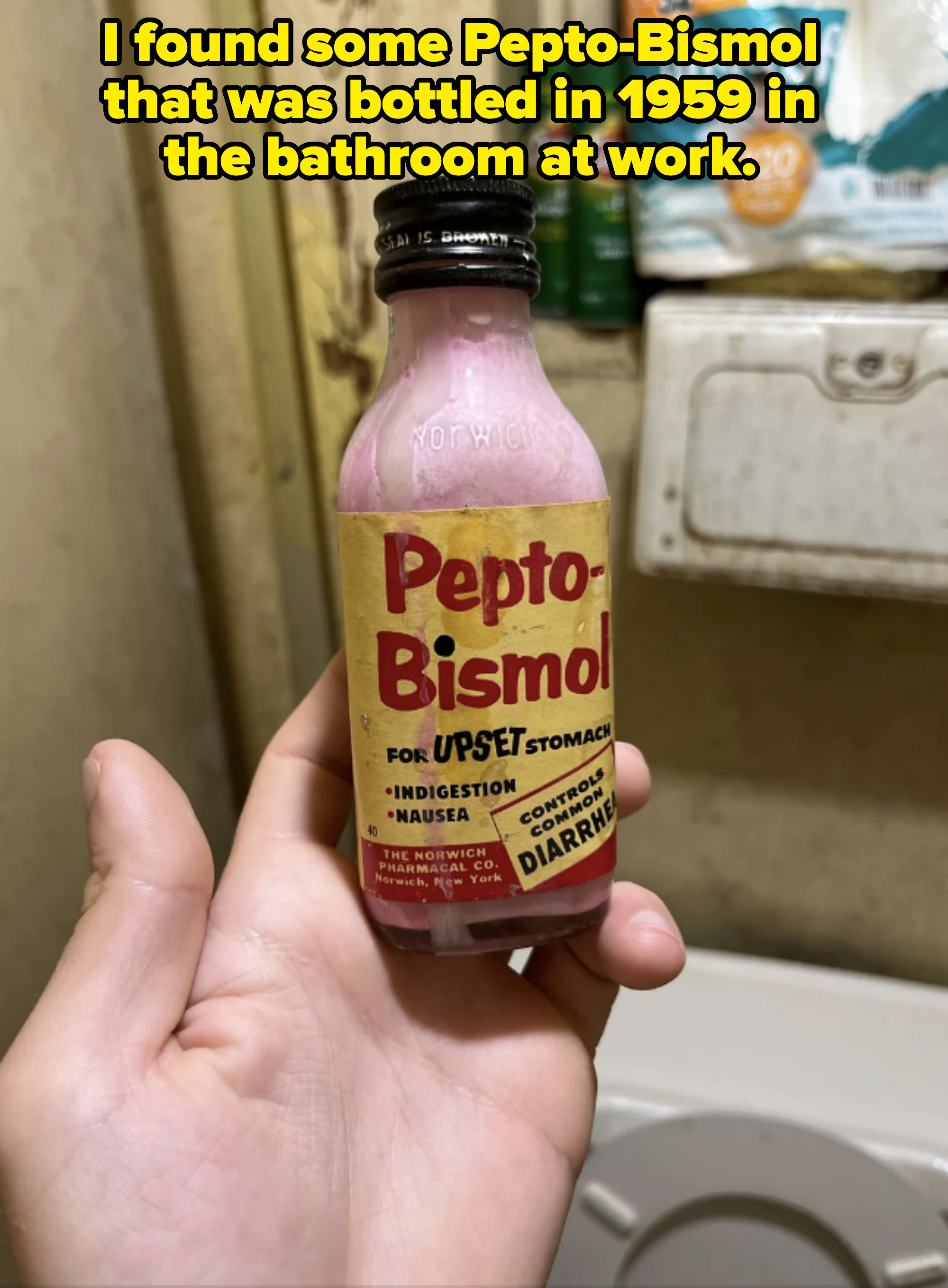 A hand holds a vintage bottle of Pepto-Bismol, labeled for upset stomach, indigestion, nausea, heartburn, and diarrhea relief. Background includes household items