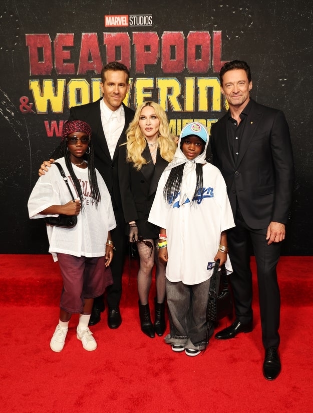 Madonna and her daughters, Stella and Estere, posing with Ryan Reynolds and Hugh Jackman on the red carpet