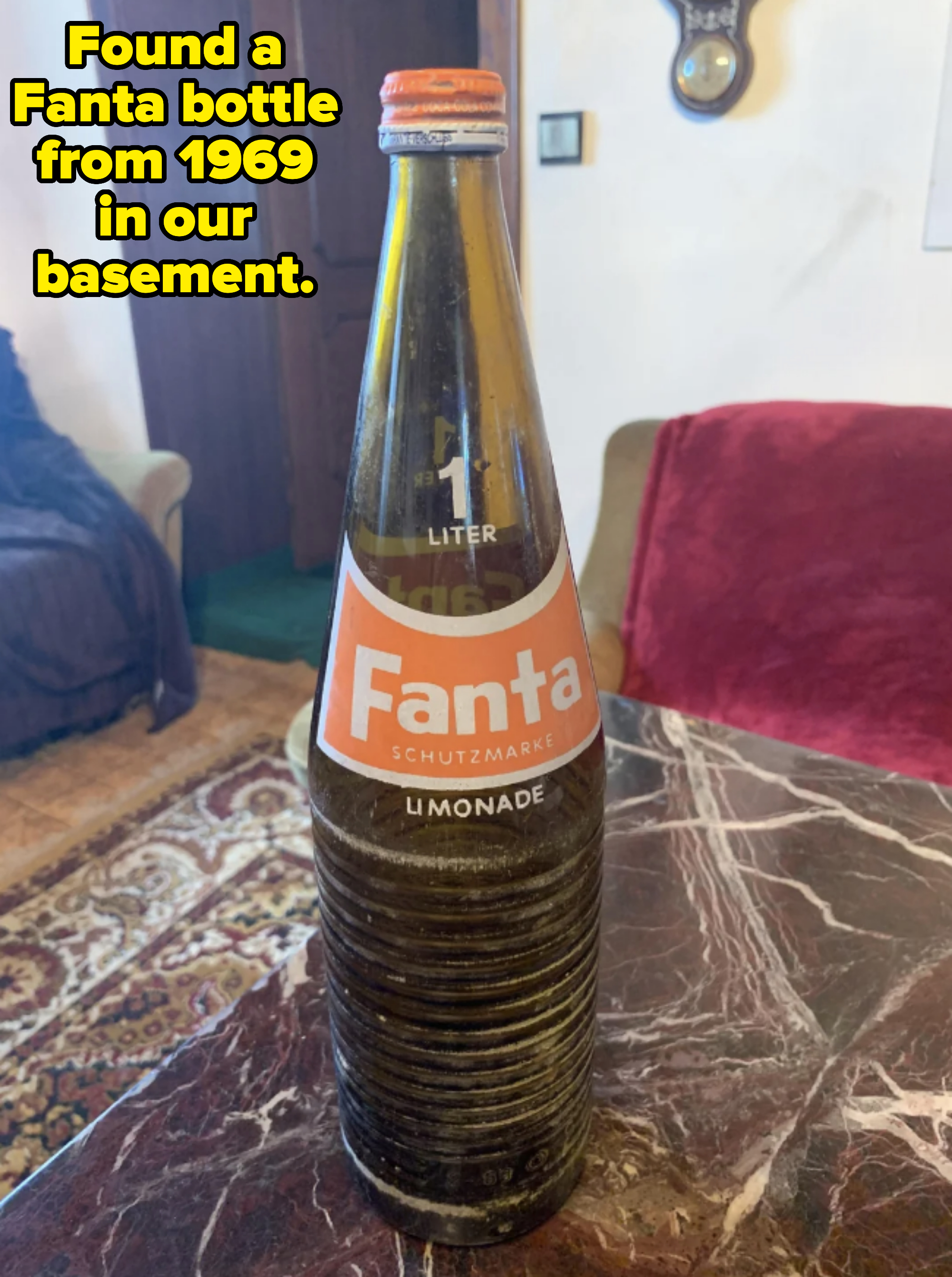 Vintage 1-liter glass bottle of Fanta lemonade on a marble table in a room with visible furniture and decor