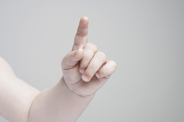 赤ちゃんが指を一本立てている手の写真。