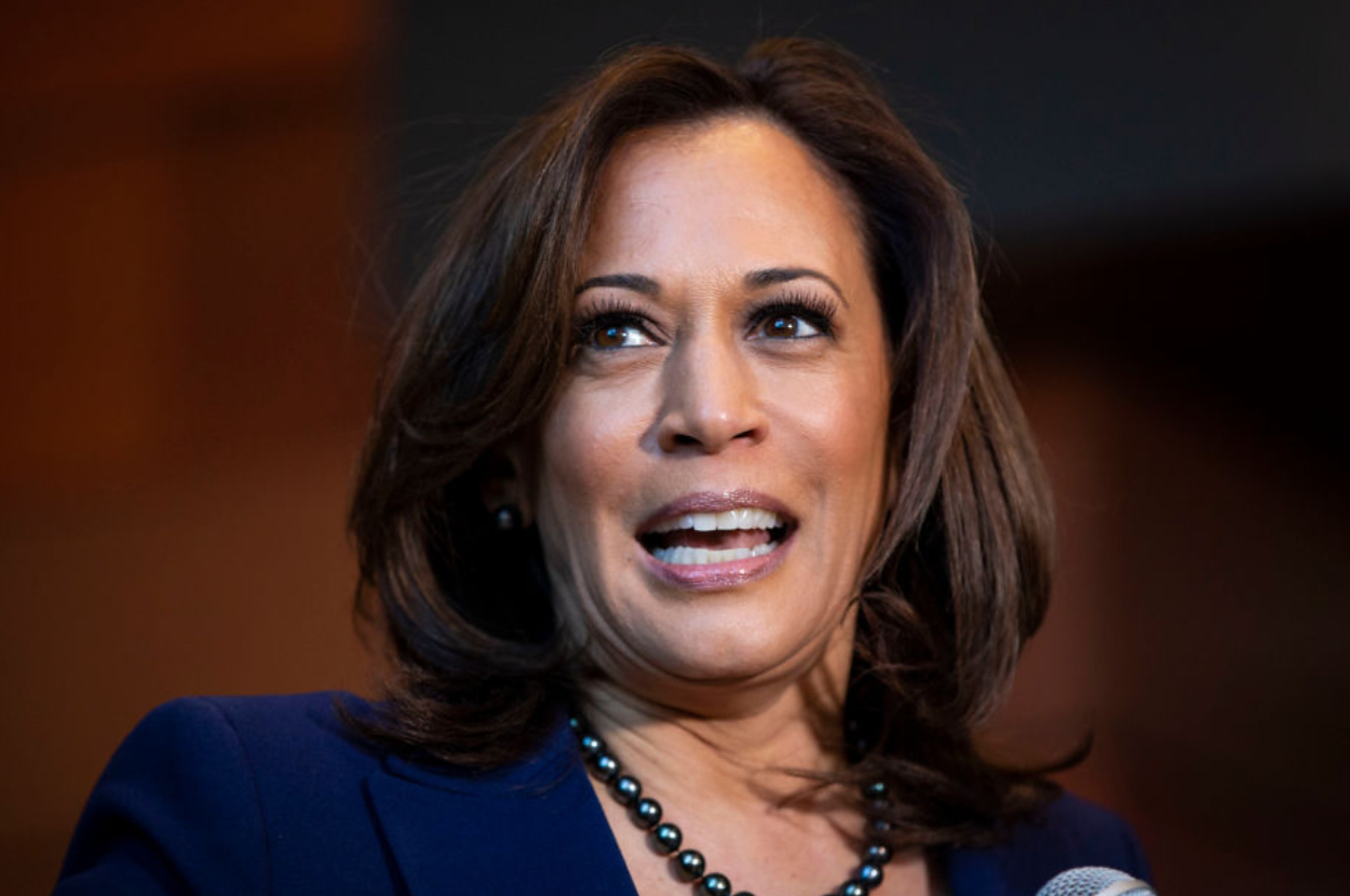 Kamala Harris speaks at an event, wearing a dark blazer and a pearl necklace