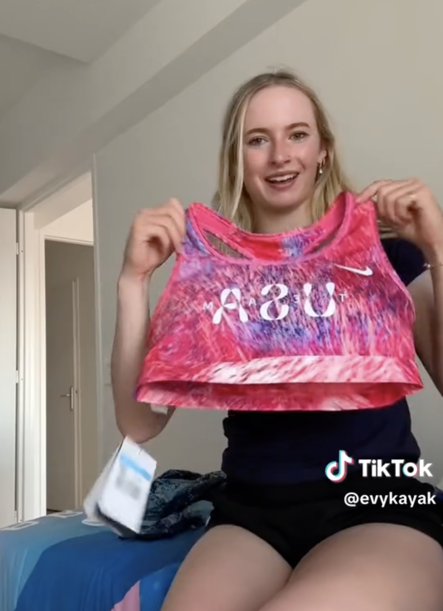 Person (name unclear) holds up an ASU athletic tank top in a casual indoor setting, appearing in a TikTok video by @evykayak