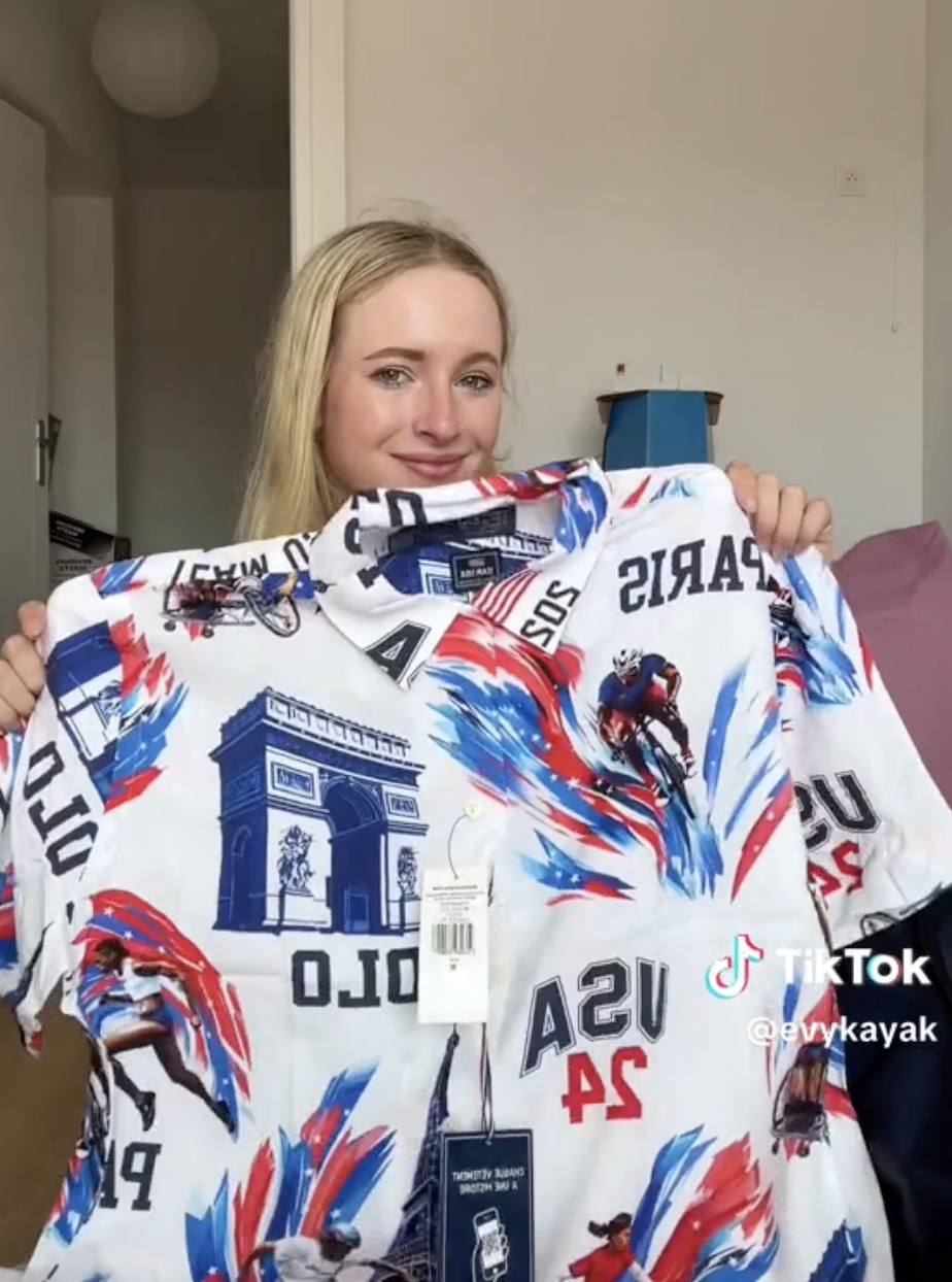 A young woman, possibly a content creator, holds up a shirt decorated with images related to Paris and the USA. The TikTok handle &quot;@svykayak&quot; is visible