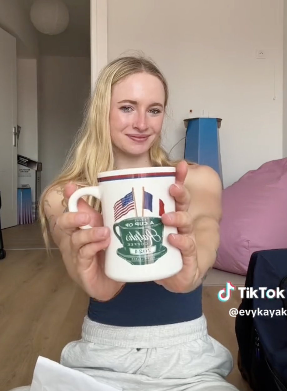 Person holding a mug with the text &quot;A Cup of Paris Coffee.&quot; TikTok username: @evykayak visible on the lower right