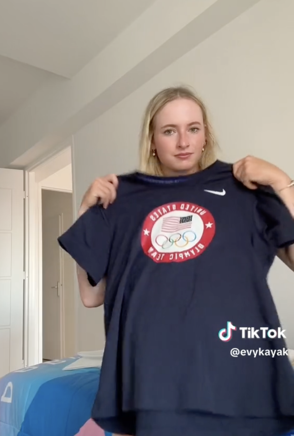 Woman, identified as TikTok user @evykayak, holds up a T-shirt with &quot;United States Olympic Team&quot; written on it