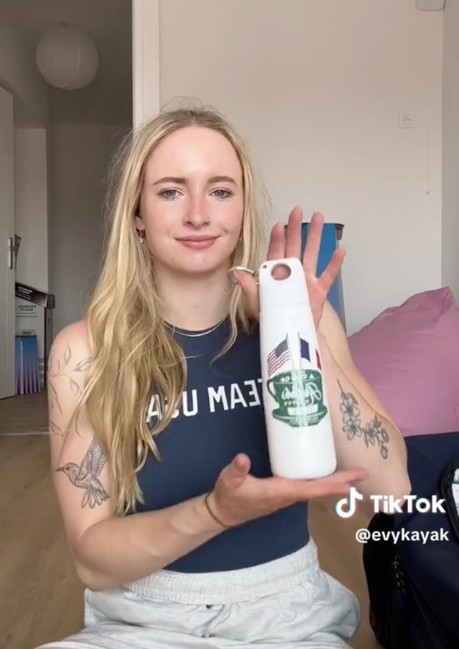 Evy Leibfarth holding a white water bottle, showcasing the design to the camera, in a TikTok video