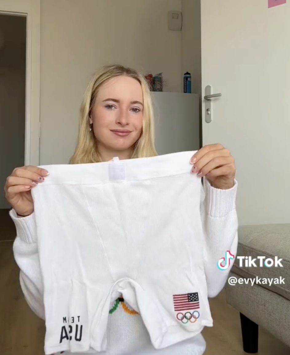 A woman holds up a pair of white shorts with &quot;Team USA&quot; and Olympic flag patches. Text overlay: TikTok @evykayak