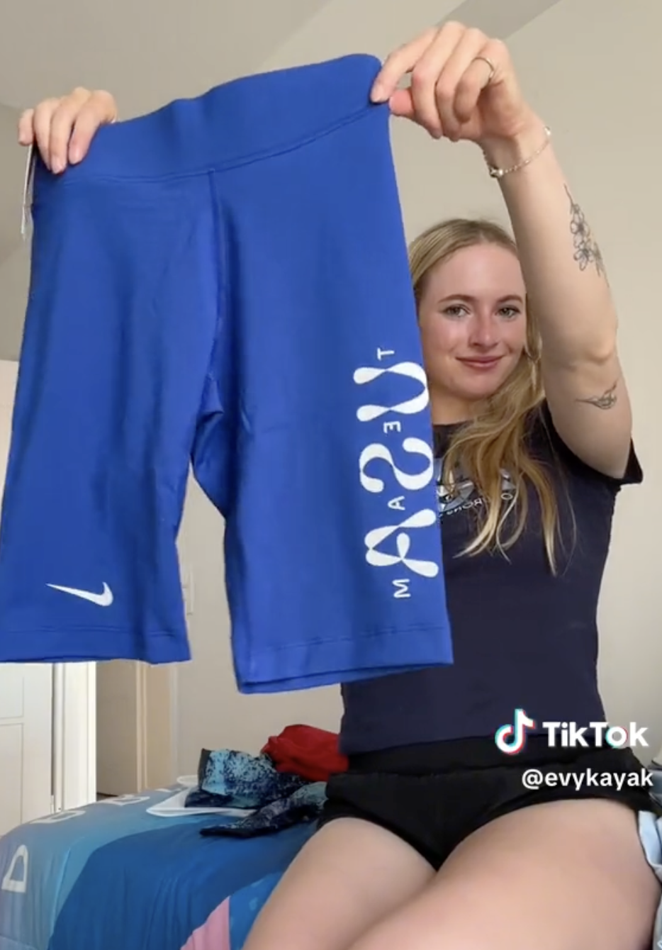 Evykayak holds up blue Team USA Nike shorts, smiling, indoors