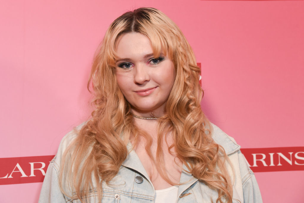 Abigail Breslin attends a Clarins event, wearing a casual light denim jacket and a white top, with loose, wavy hair