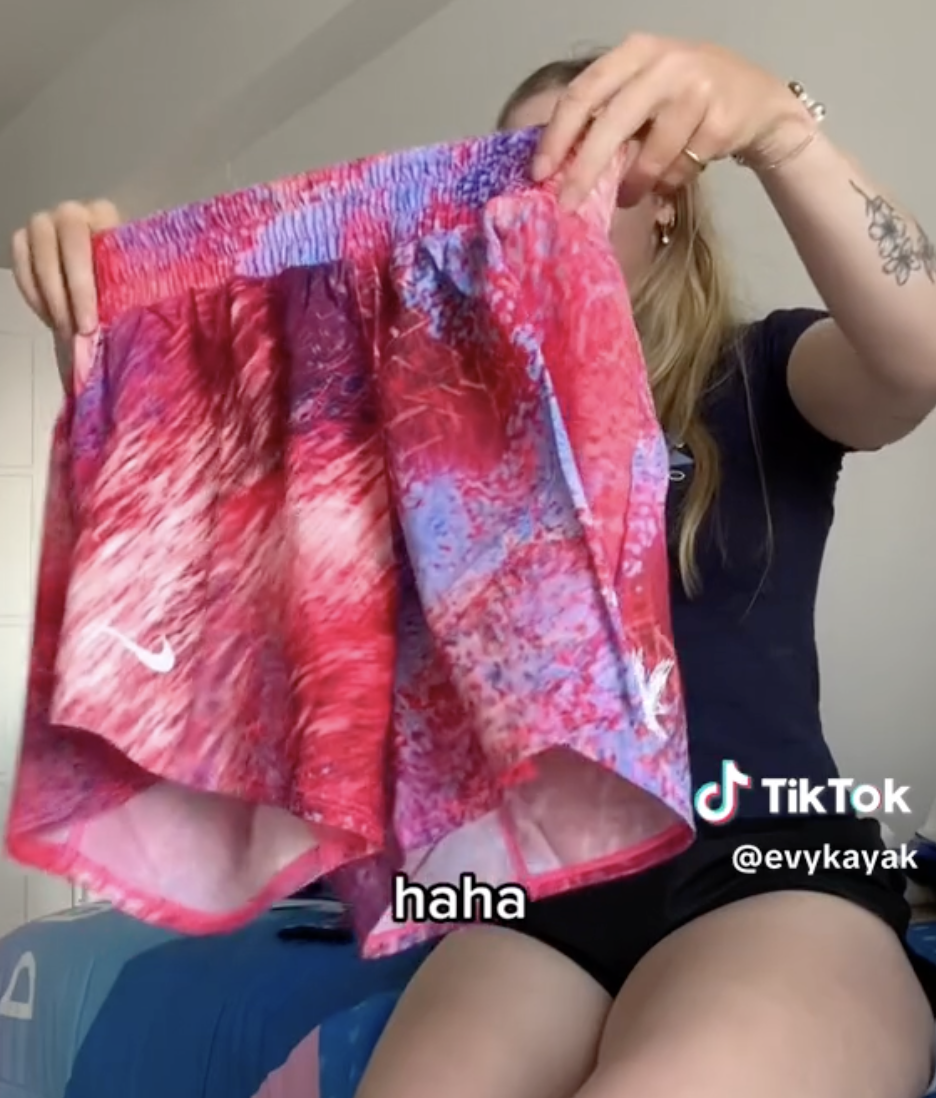 A person holds up a pair of colorful shorts, showing them off in front of a bed. The TikTok username @evykayak is visible. The text overlay reads, &quot;haha.&quot;
