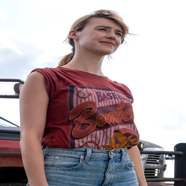 Daisy Edgar Jones and Glen Powell stand in a grassy field in casual attire with a rugged vehicle in the background