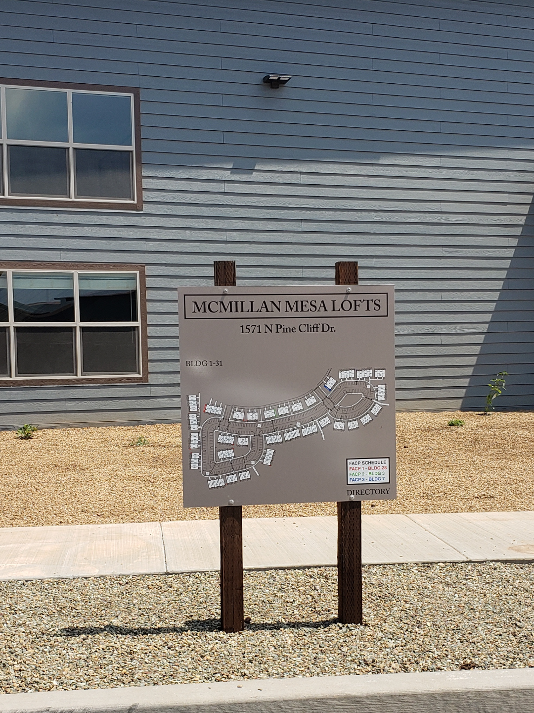 A sign reads &quot;McMillan Mesa Lofts, 1571 N Pine Cliff Dr.&quot; with a map of the lofts layout in front of a building