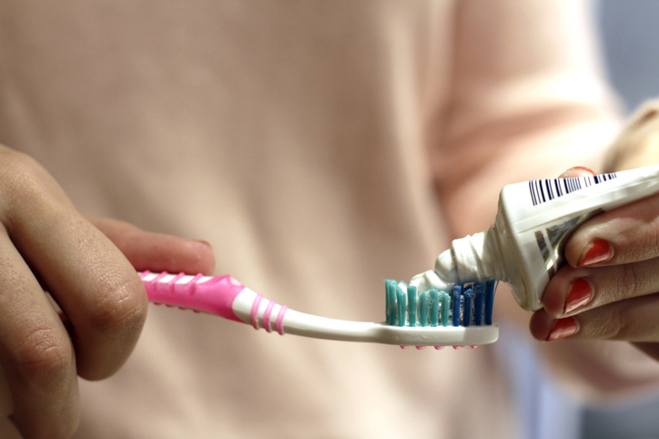 A person is applying toothpaste to a toothbrush, preparing to brush their teeth