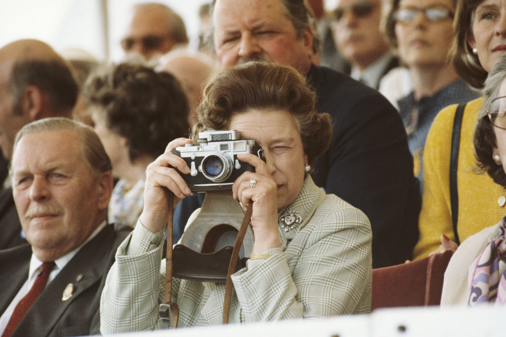 Group of people seated, with an older woman in the foreground taking a photo with a camera