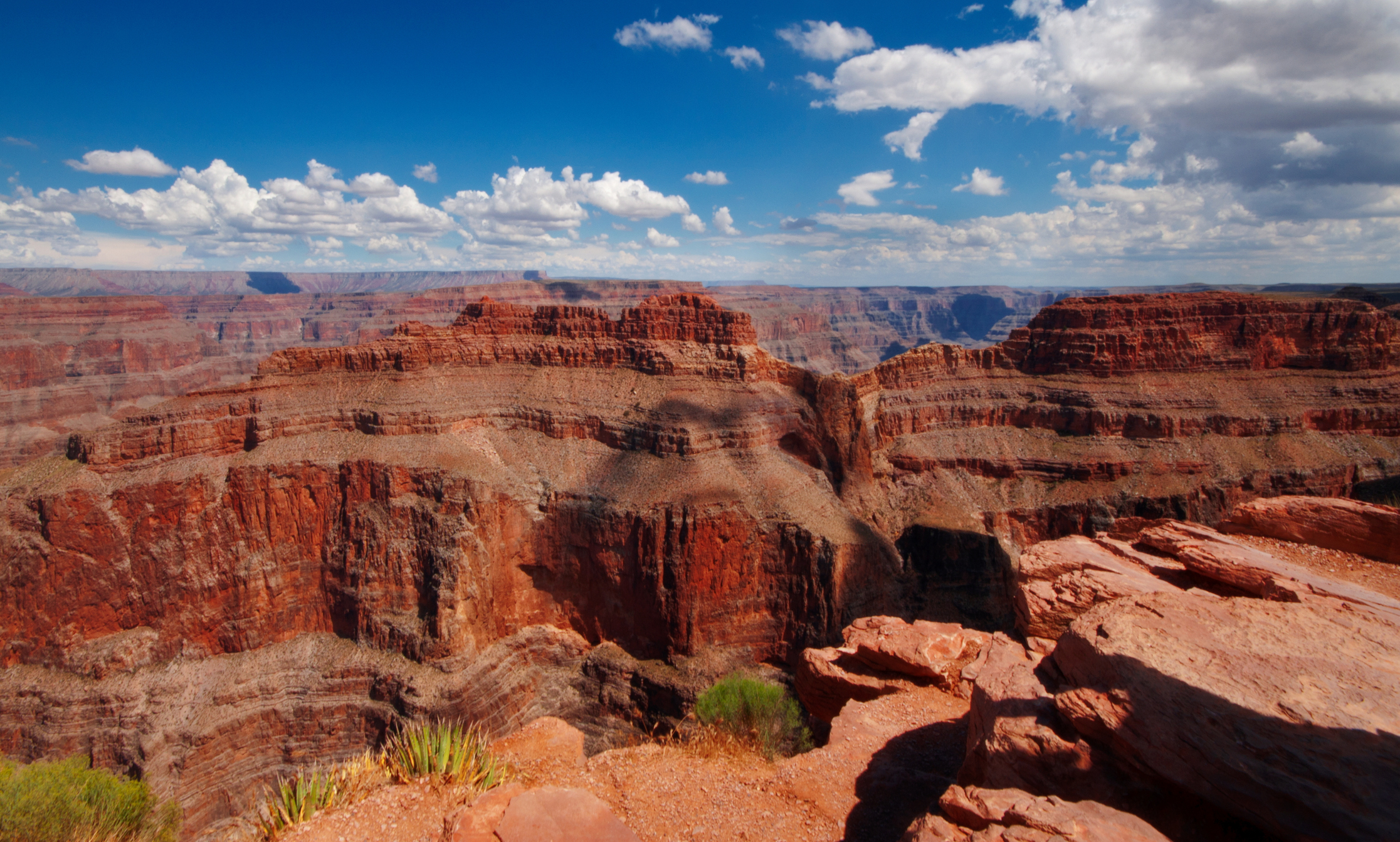A stunning view of the Grand Canyon with rugged, layered rock formations under a sky dotted with fluffy clouds