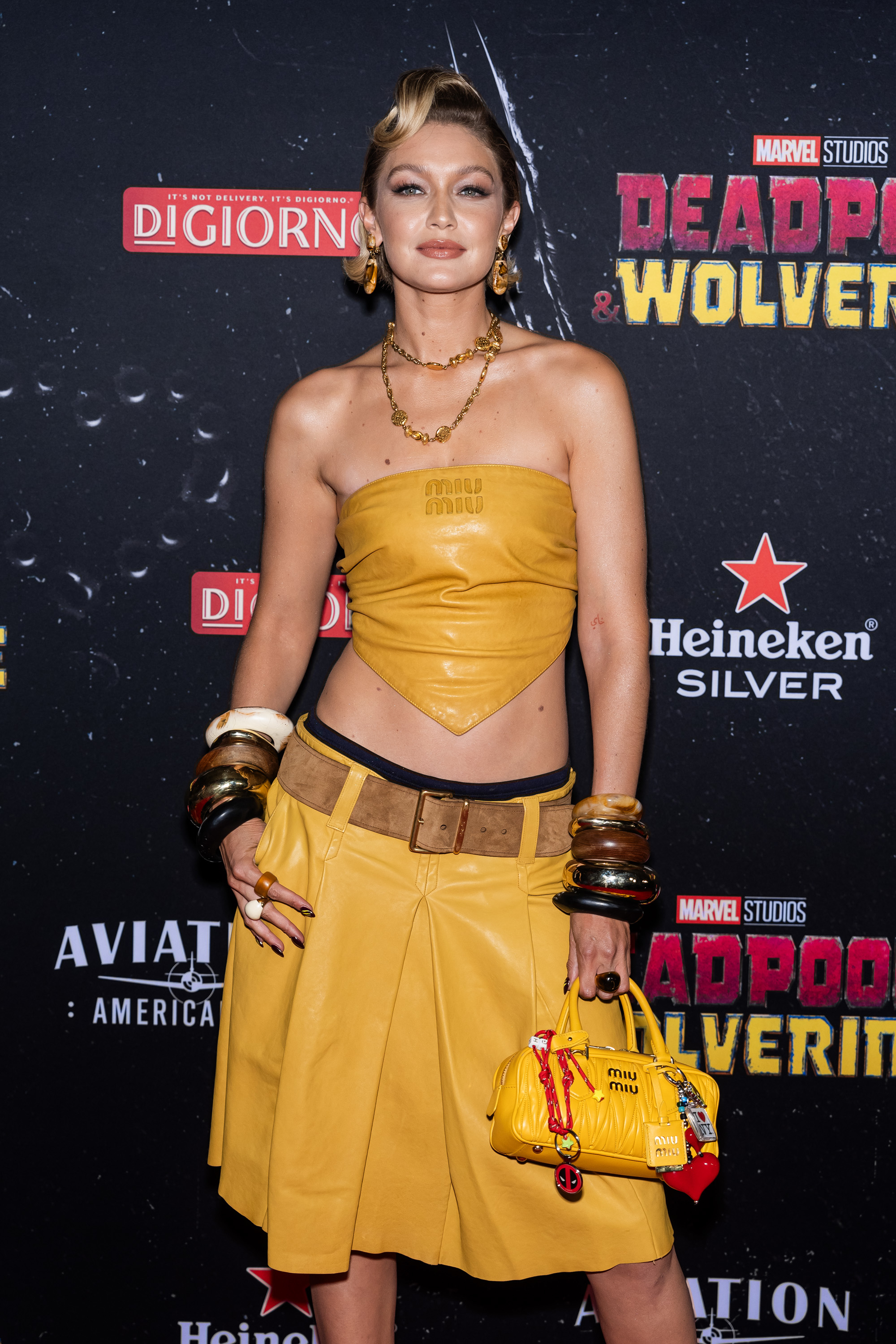 Gigi Hadid poses at a red carpet event for "Deadpool 3" and "Wolverine" in a stylish, strapless yellow top and a matching skirt