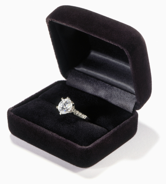 An open velvet ring box revealing a diamond engagement ring inside