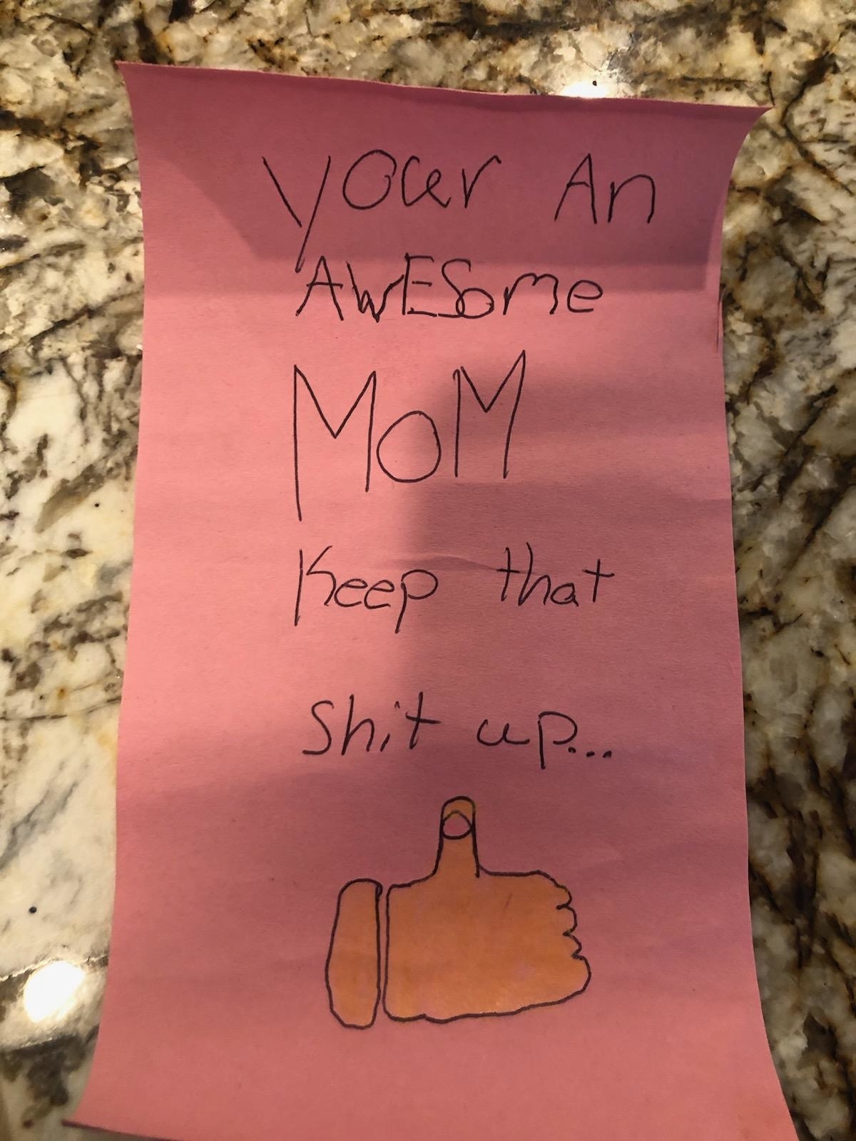 Handwritten note on pink paper saying, "You’ re an awesome mom. Keep that shit up… " with a drawing of a thumbs-up