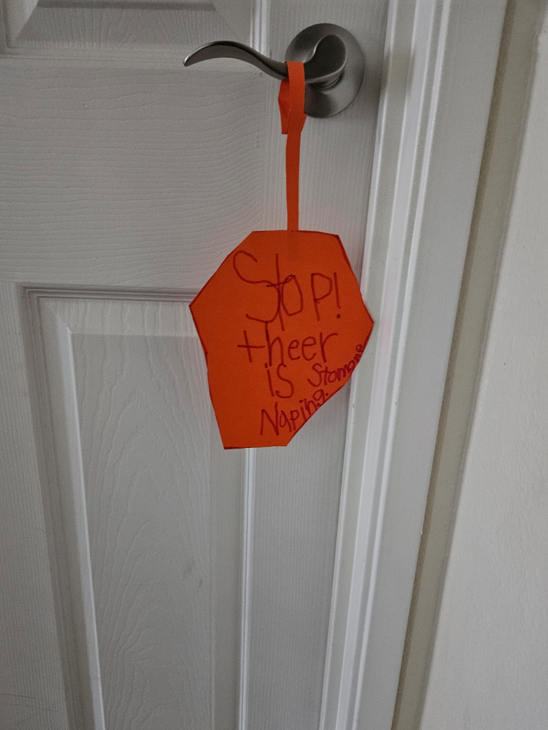 A handmade sign on a door handle reads, "Stop! Theer is stoming Naping."