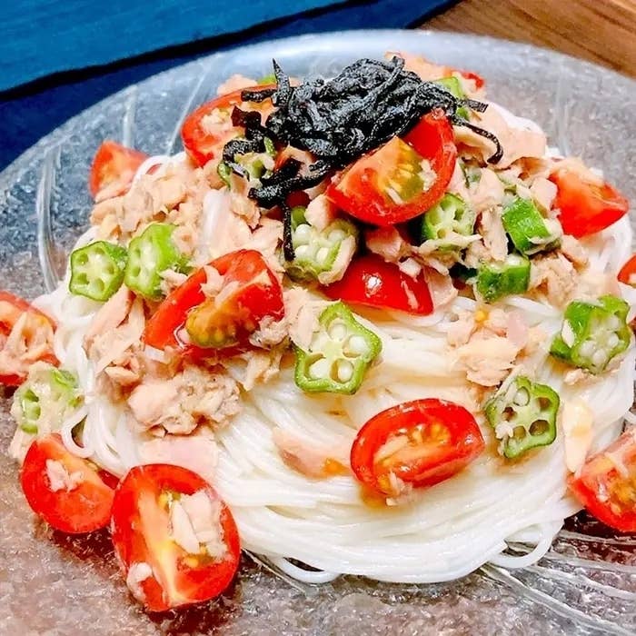 ガラス皿に盛られた細い素麺、上にはトマト、オクラ、ツナ、刻み海苔が乗っています。