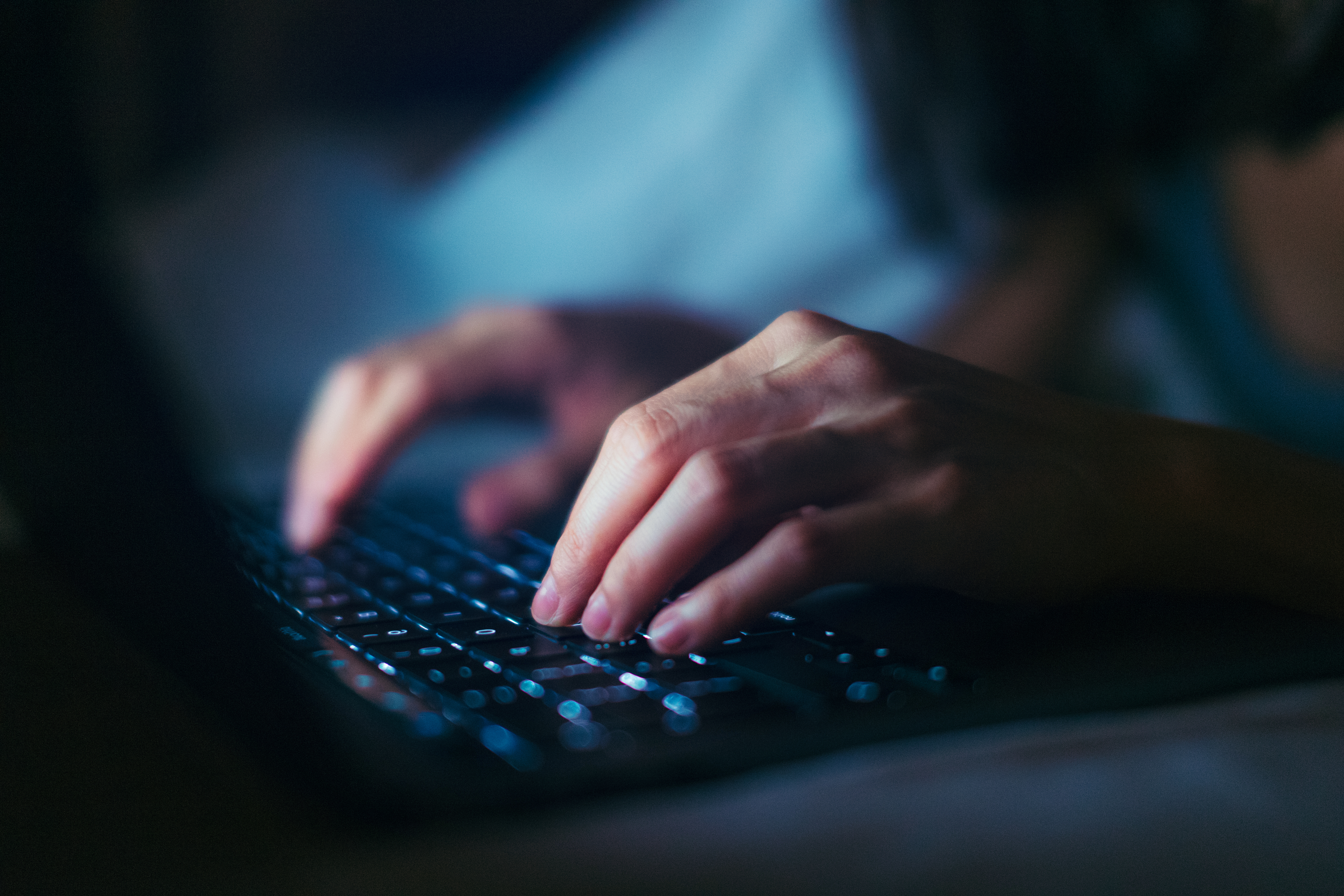 A close-up of hands typing on a laptop keyboard