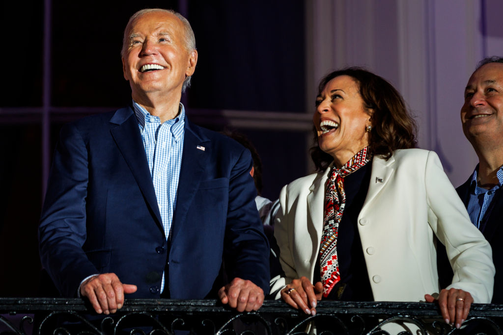 Joe Biden and Kamala Harris smiling and standing together at an event. They are both dressed in formal attire