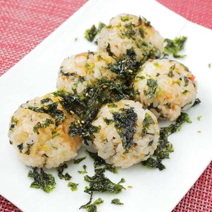 白い皿に盛り付けられた5つのおにぎりがのりで飾られている。