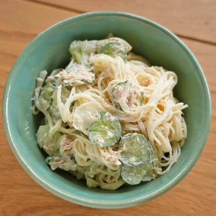 クリーミーなソースで和えられたパスタと薄切りのきゅうりがボウルに入っています。