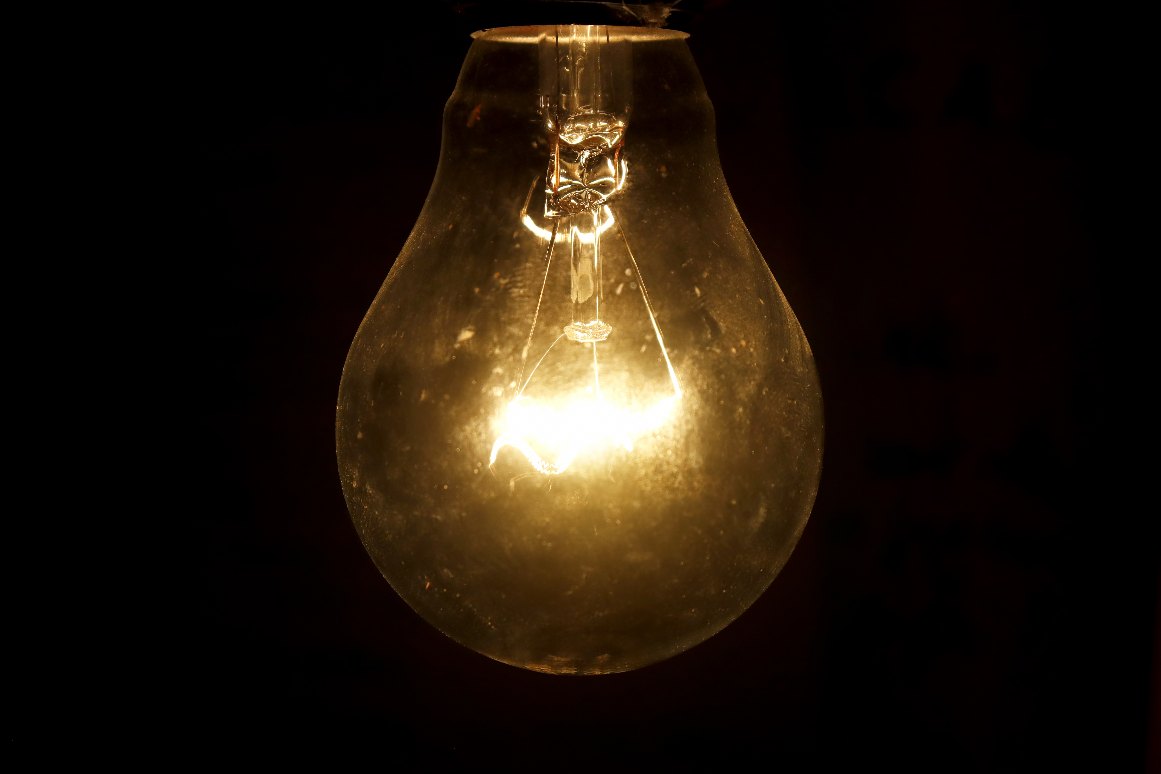 A lit incandescent light bulb glowing brightly against a dark background