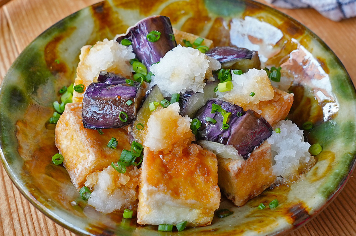 揚げ出し豆腐と焼きナスの大根おろしがけが、和風の器に盛り付けられた料理。和柄の布が添えられている。