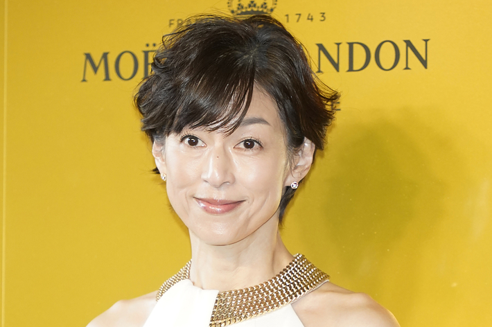 有名な俳優がシンプルな白のドレスを着て、MOËT CHANDONの背景の前でポーズをとっています。