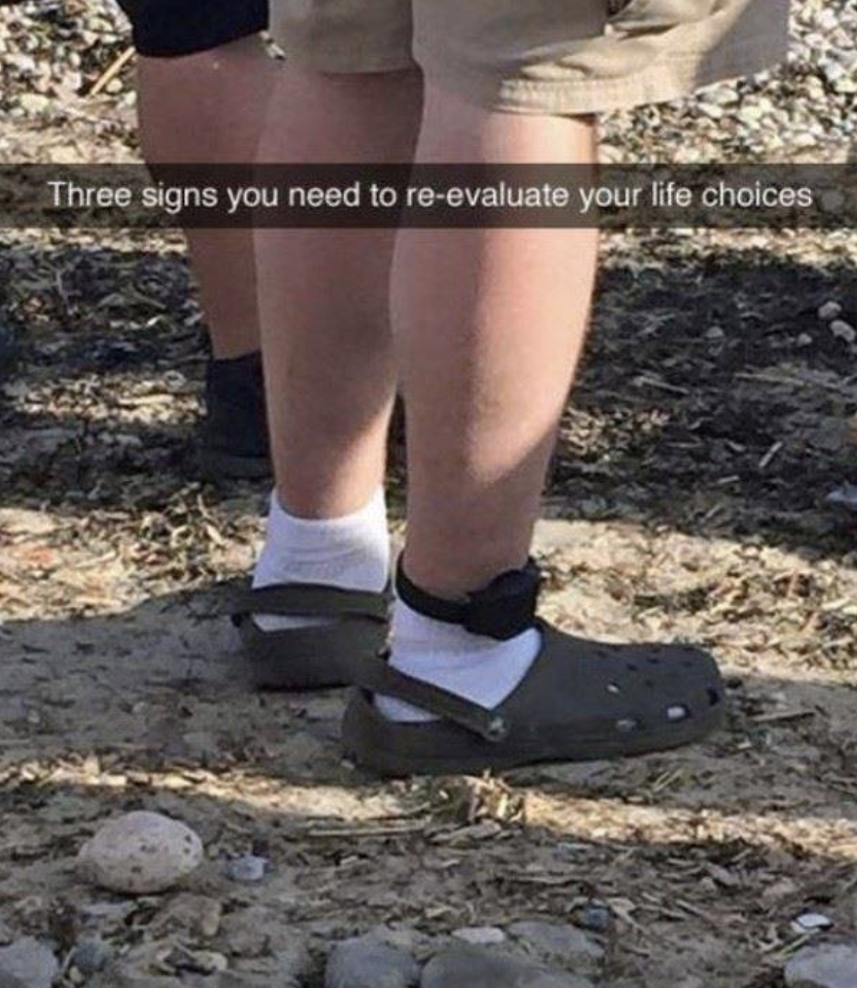 Close-up of legs in socks and Crocs with a caption: "Three signs you need to re-evaluate your life choices" visible across the center of the image