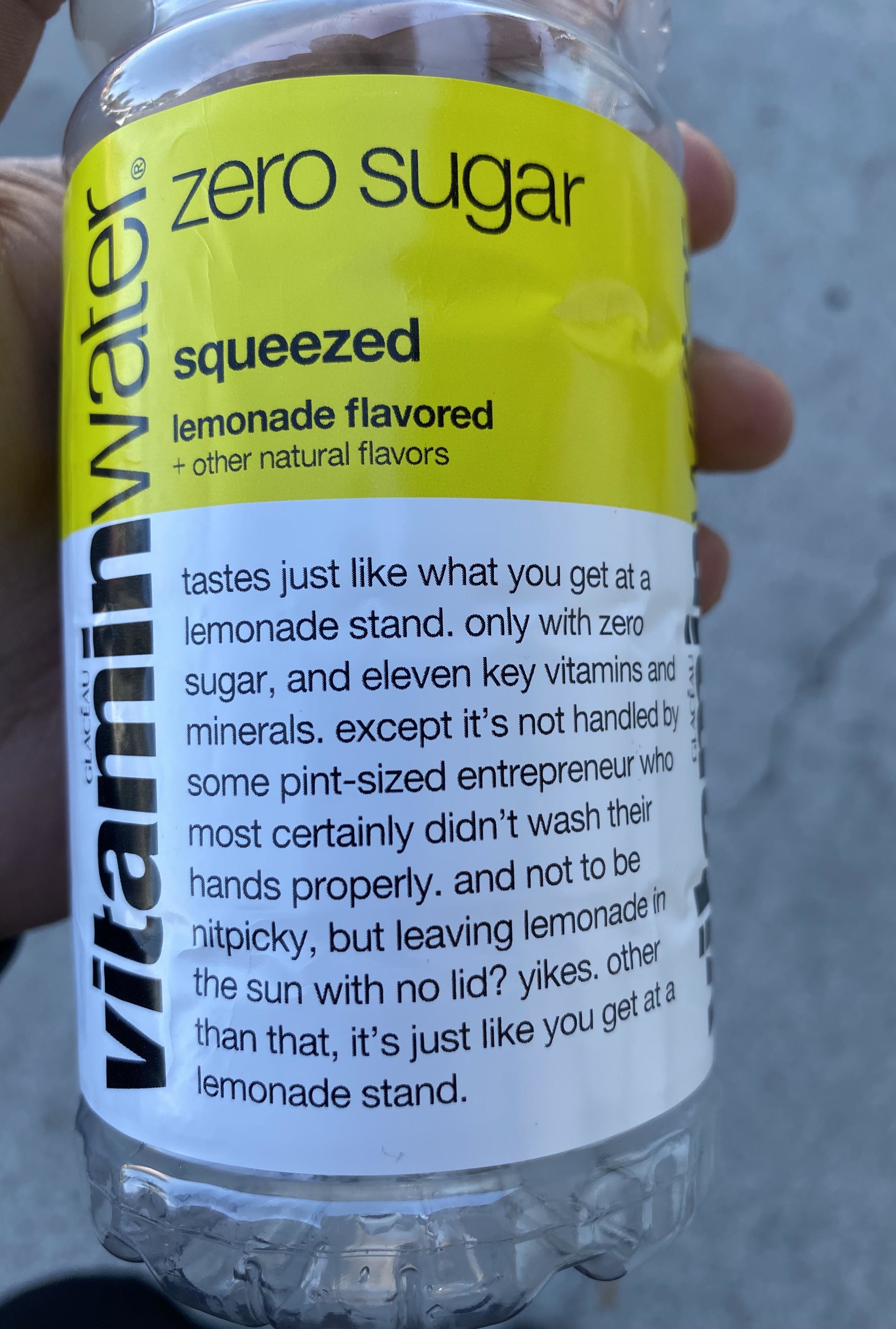 A bottle of Vitamin Water Zero Sugar Lemonade with humorous text about its taste and handling, compared to typical lemonade stands