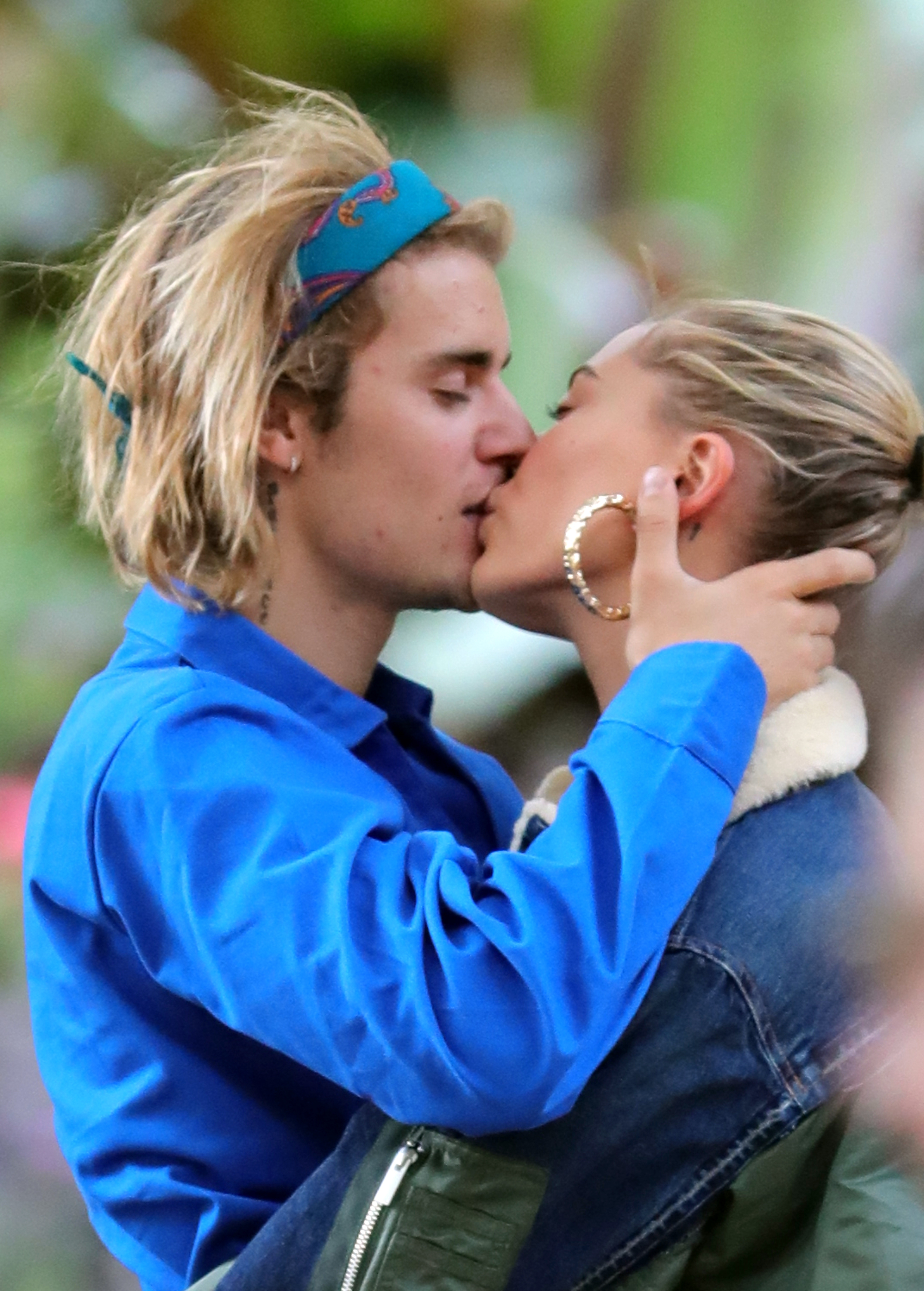 Justin Bieber e Hailey Baldwin se beijam, com Justin usando uma faixa na cabeça e uma jaqueta, e Hailey com brincos de argola e uma jaqueta jeans