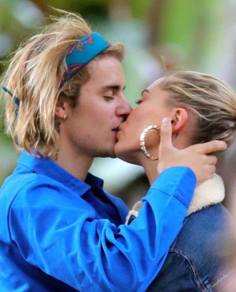 Justin Bieber e Hailey Baldwin se beijam, com Justin usando uma faixa na cabeça e uma jaqueta, e Hailey com brincos de argola e uma jaqueta jeans