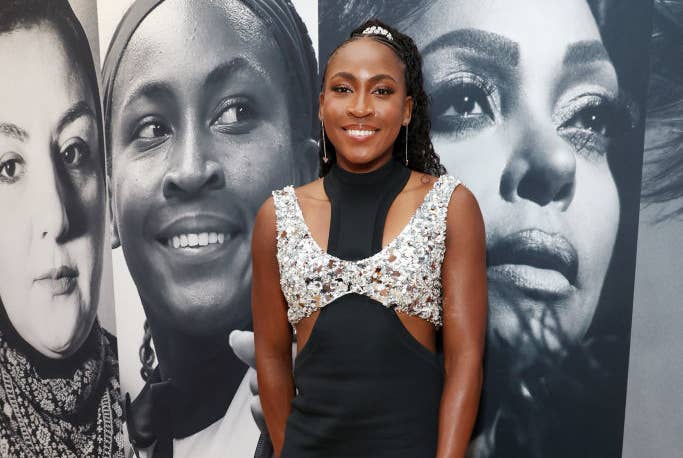 Coco Gauff in an elegant black evening gown with silver sequins, standing in front of her portrait at an event