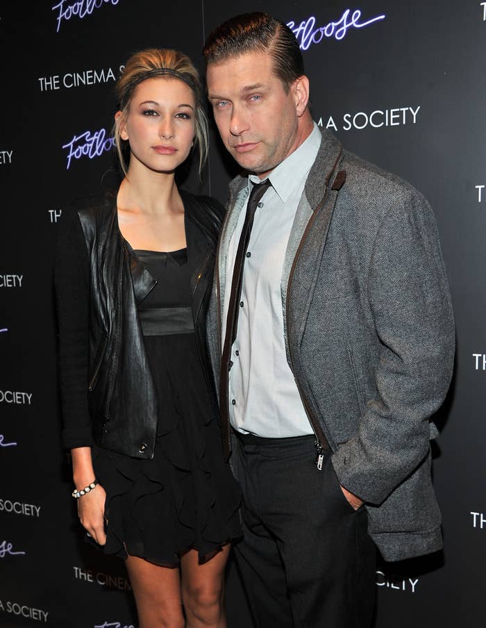 Hailey Bieber in a ruffled black dress and leather jacket, posing with Stephen Baldwin, who is wearing a jacket over a shirt and tie, at a Footloose event