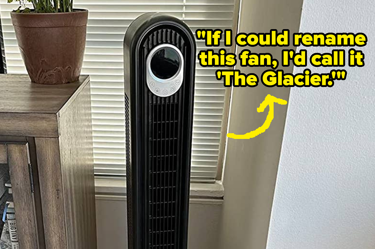 A modern oscillating tower fan next to a potted plant on a TV stand, with a TV showing an A&E channel logo