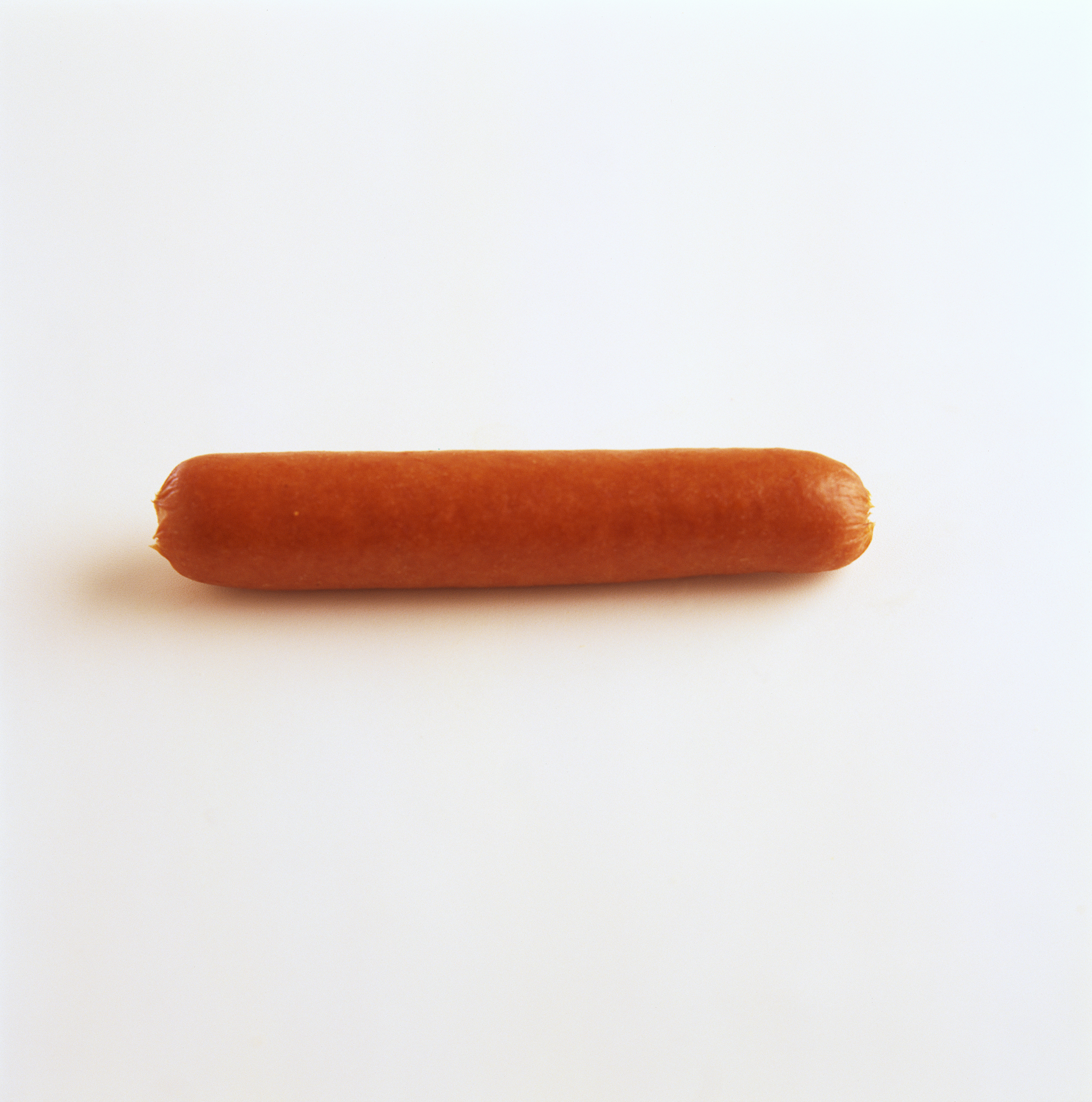 A single uncooked hot dog on a plain white background