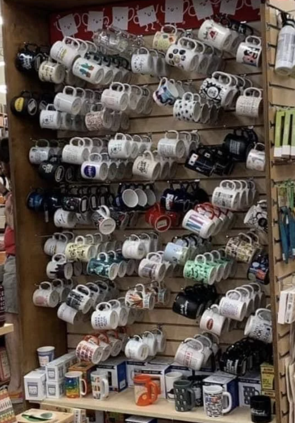 Shelf filled with various mugs of different designs and sizes displayed in a store