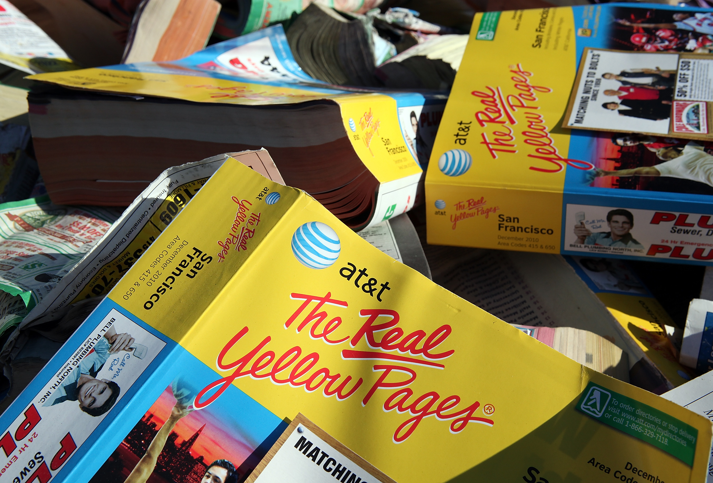 A pile of AT&T phone books titled "The Real Yellow Pages," featuring multiple ads and contact information sections