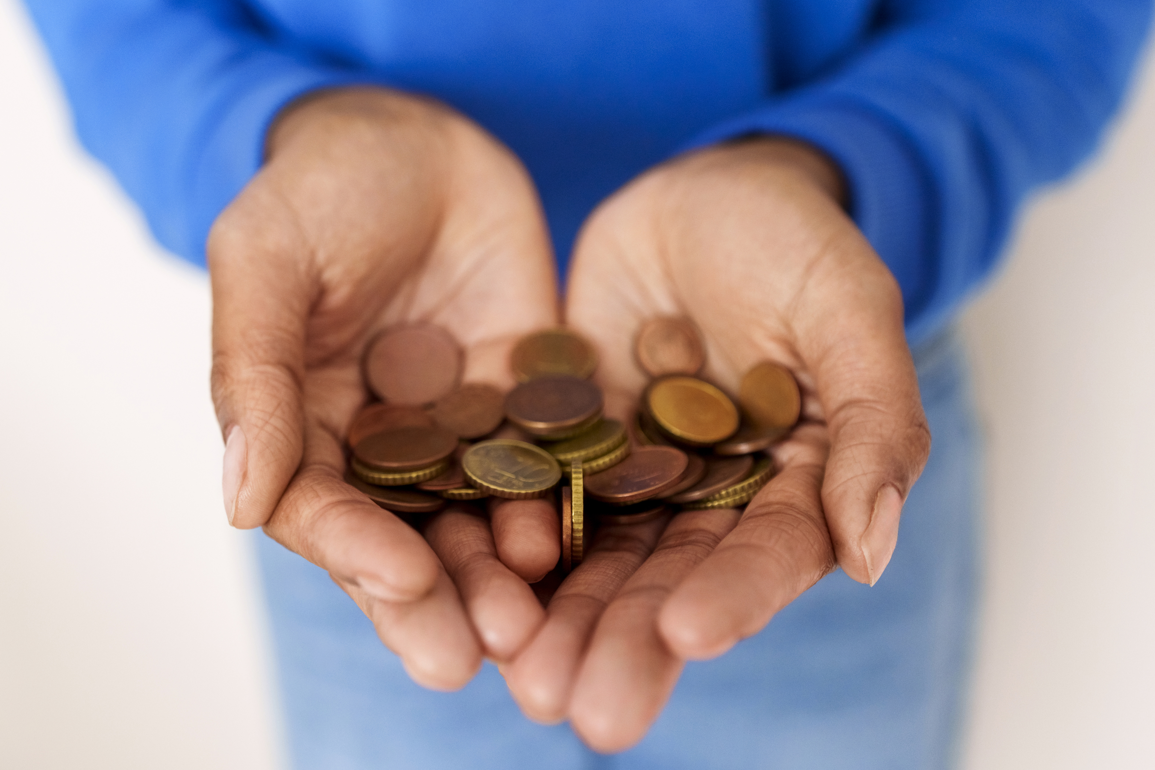 Hands holding various coins, mostly pennies