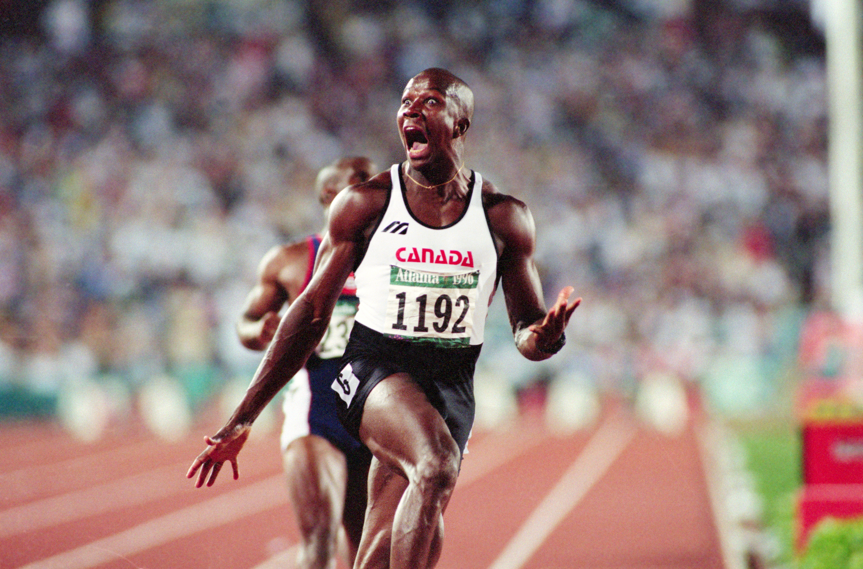 An athlete with bib number 1192, representing Canada, celebrates passionately on a running track during a competition