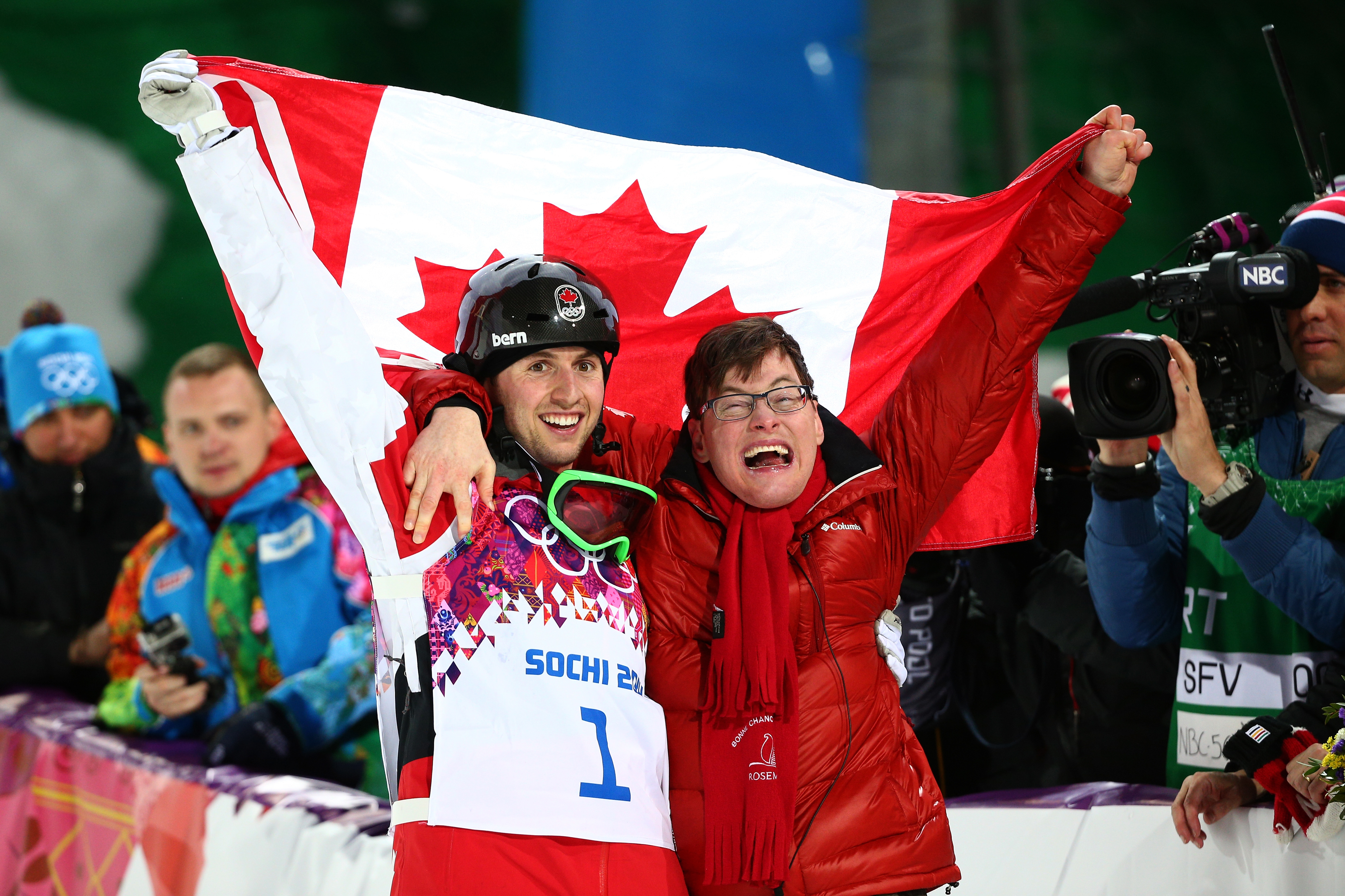 A Canadian athlete celebrates with another person wrapped in a Canadian flag at the Sochi 2014 Winter Olympics