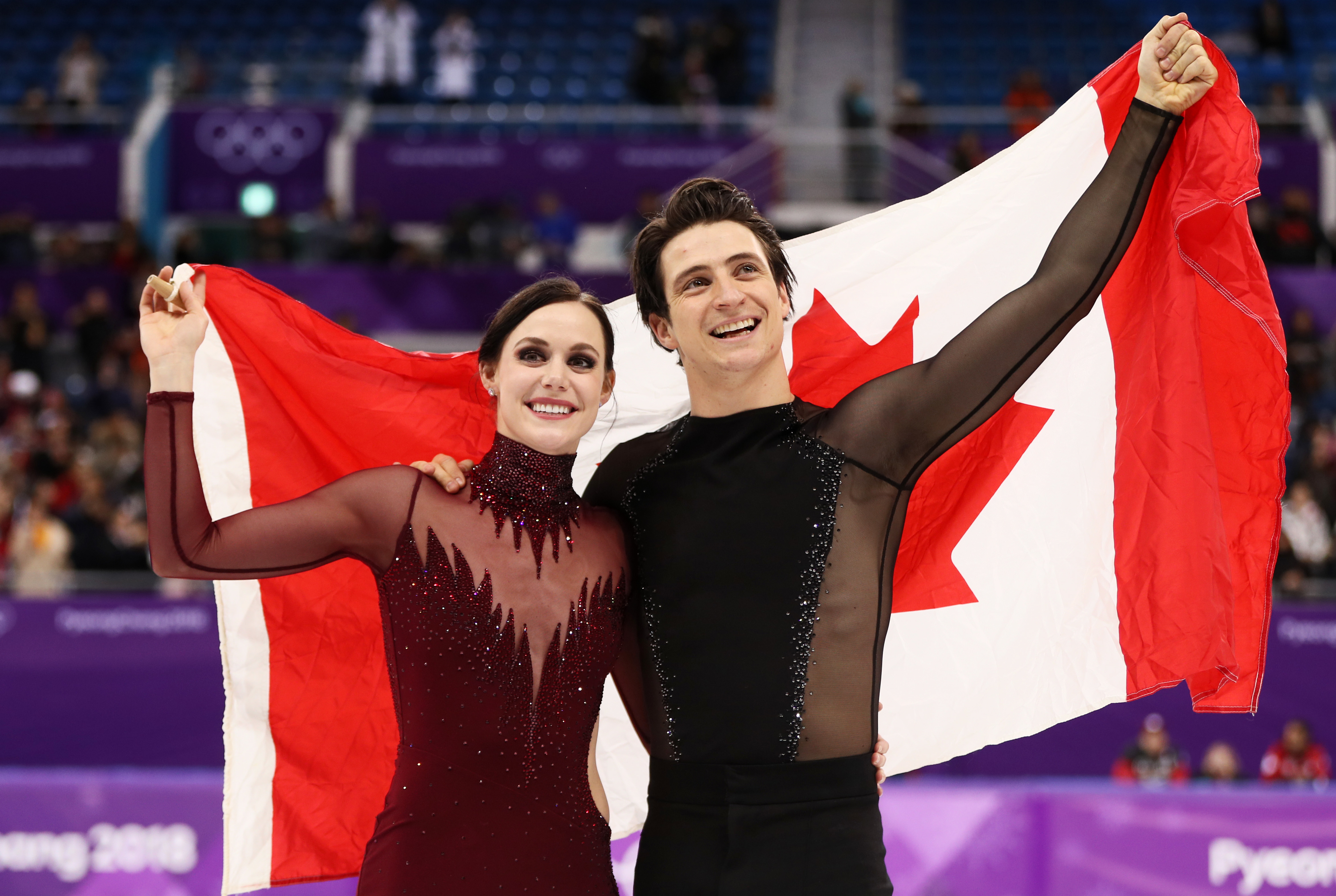 Tessa Virtue and Scott Moir, in figure skating costumes, celebrate with the Canadian flag at the 2018 Winter Olympics