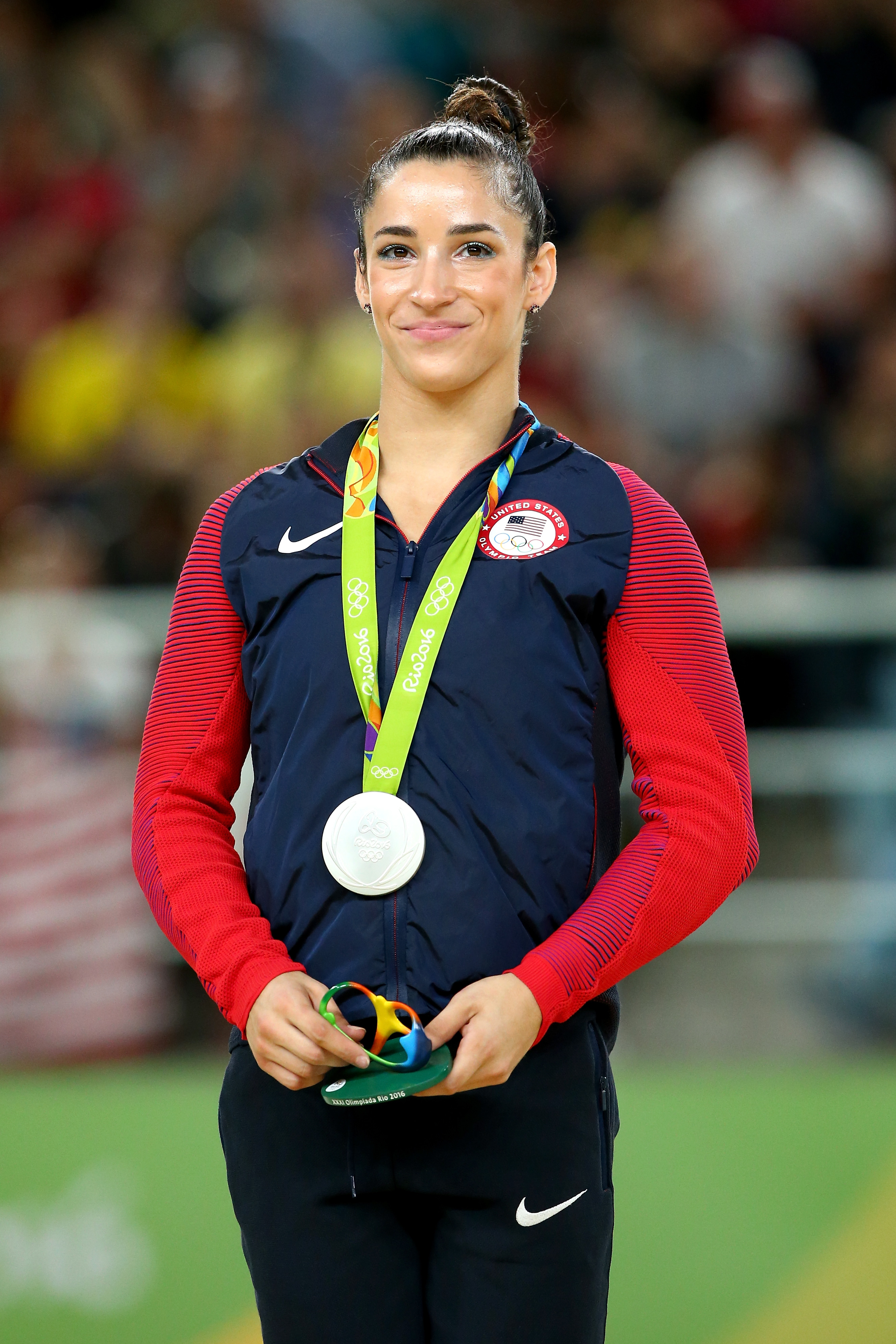 Aly Raisman at the Olympics wearing a Team USA jacket and holding her silver medal