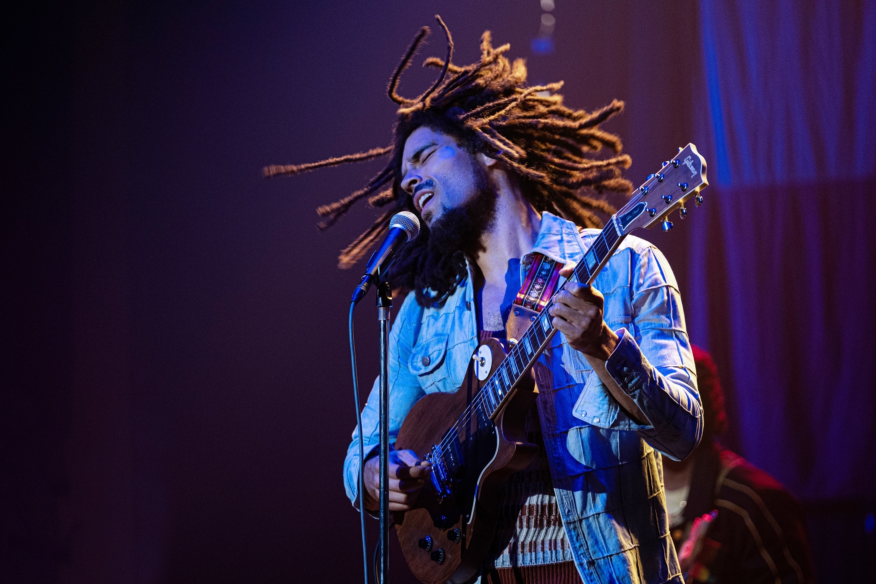 Musician passionately playing guitar and singing on stage with dynamic lighting and expressive posture